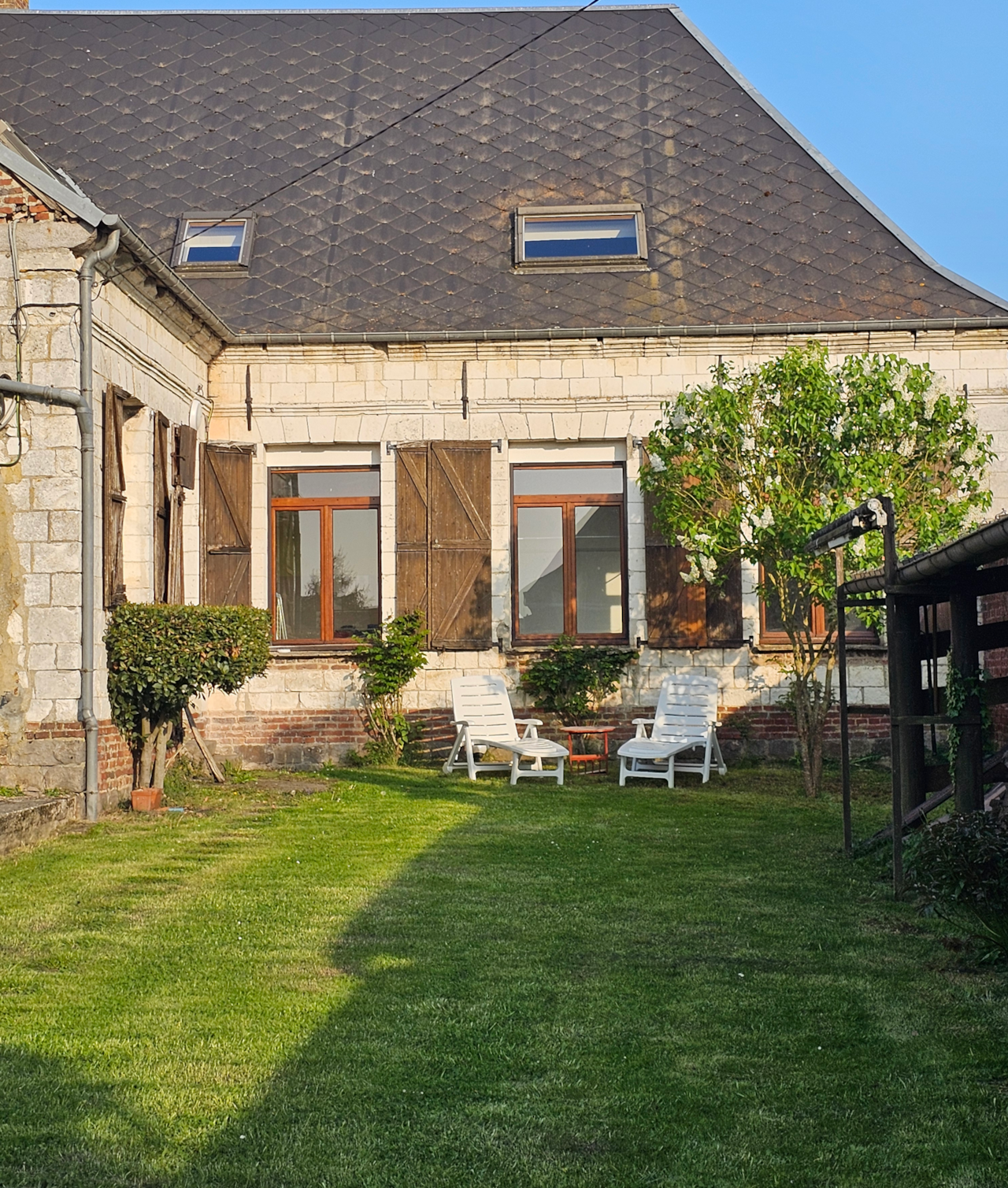 Façade arrière tout en pierres et jardin invitant à la détente