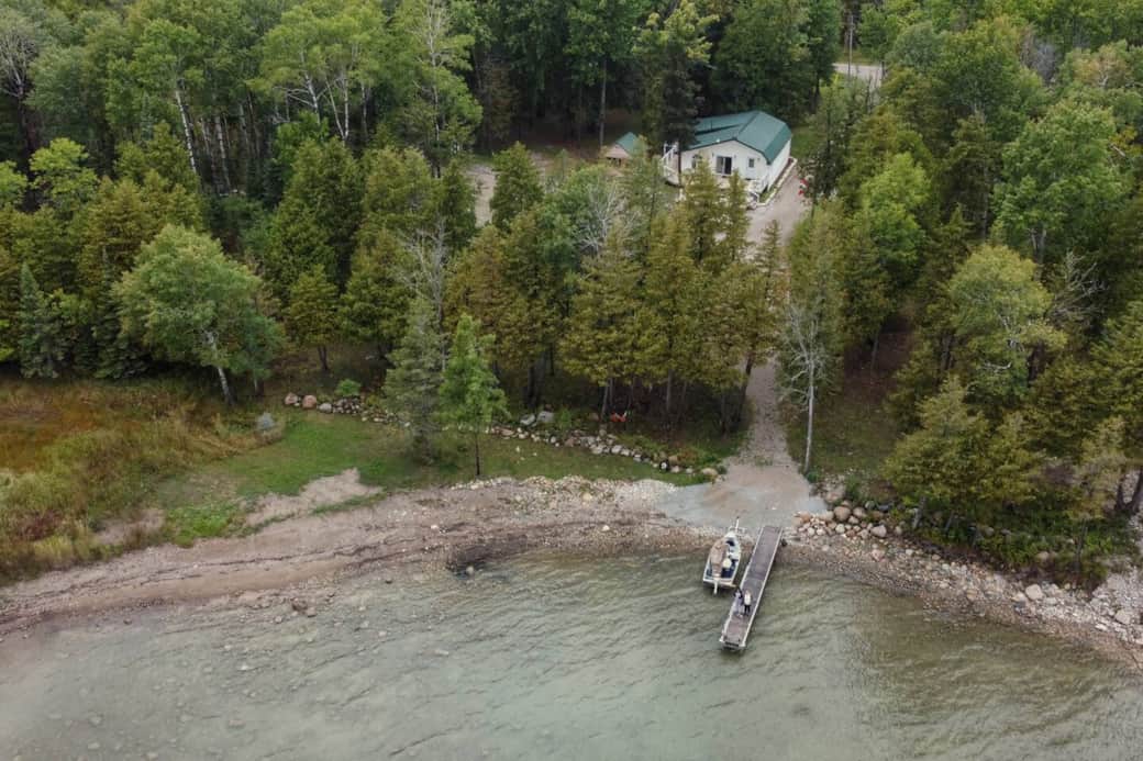 Aerial view showing the cottage, private shoreline, and dock access on beautiful Lake Huron.
