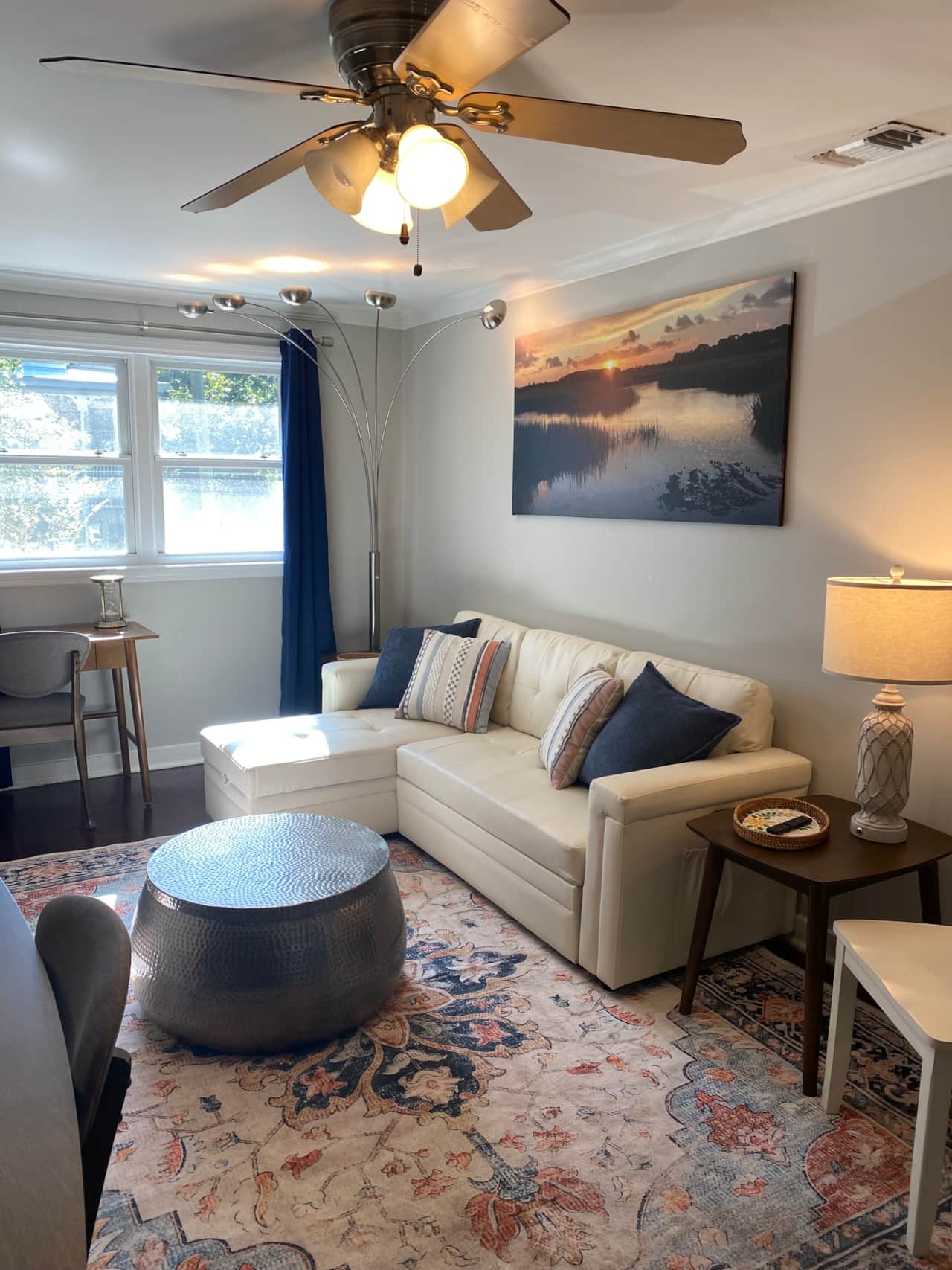 Sunlit living room with cozy sectional, local art, and a warm, inviting atmosphere.