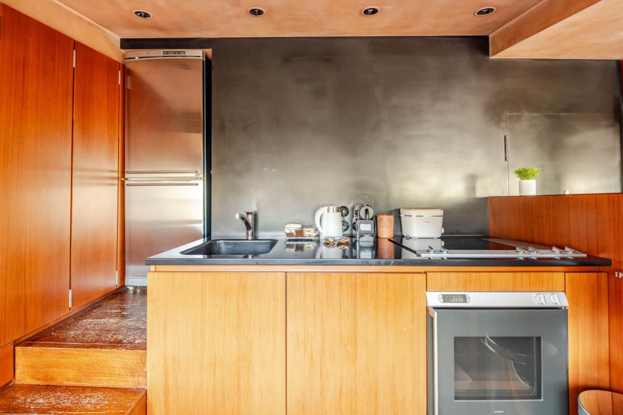 Cocina con armarios altos de madera, horno y encimera