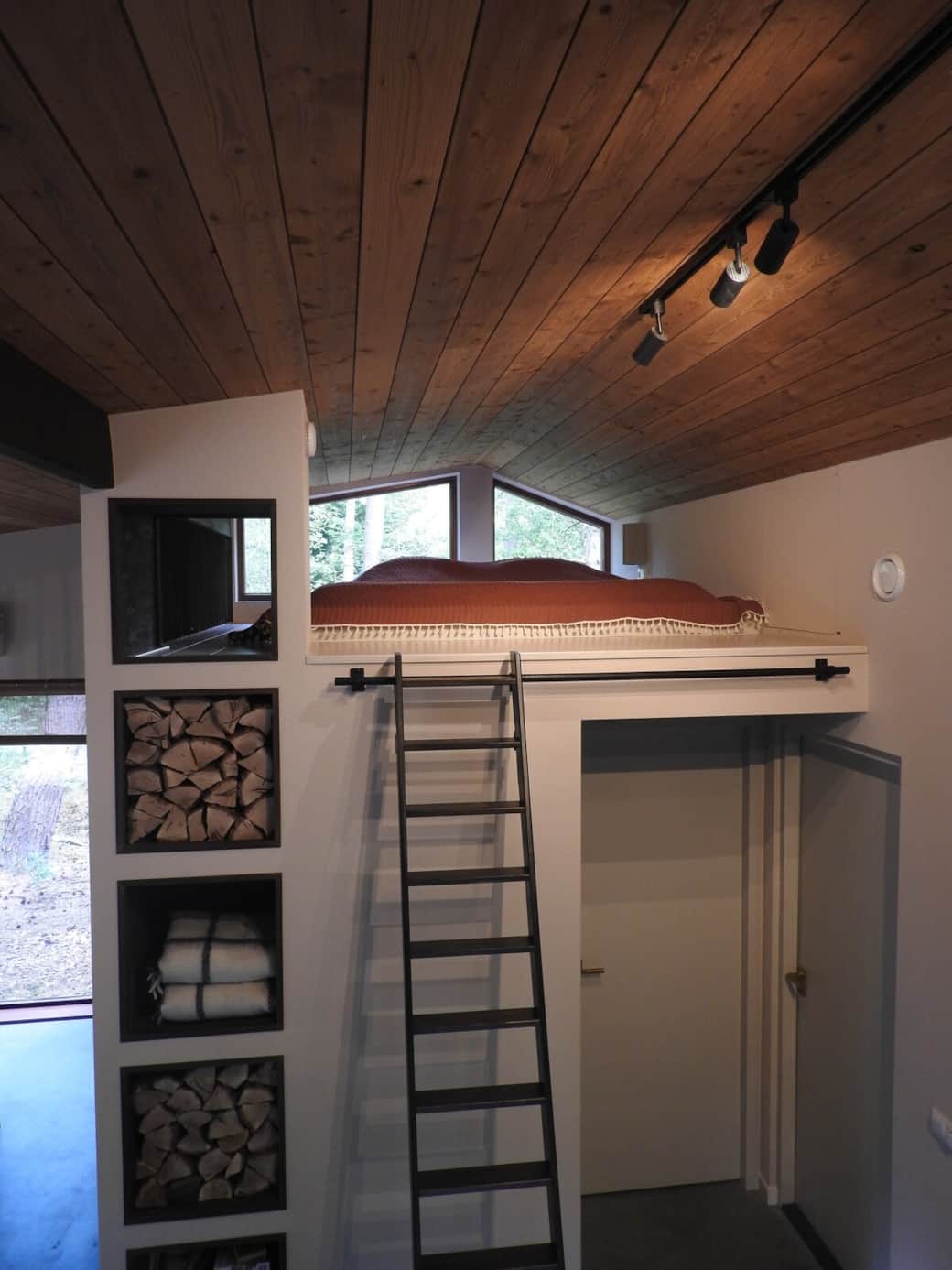 Loft sleeping area under wooden ceiling and overlooking the forest