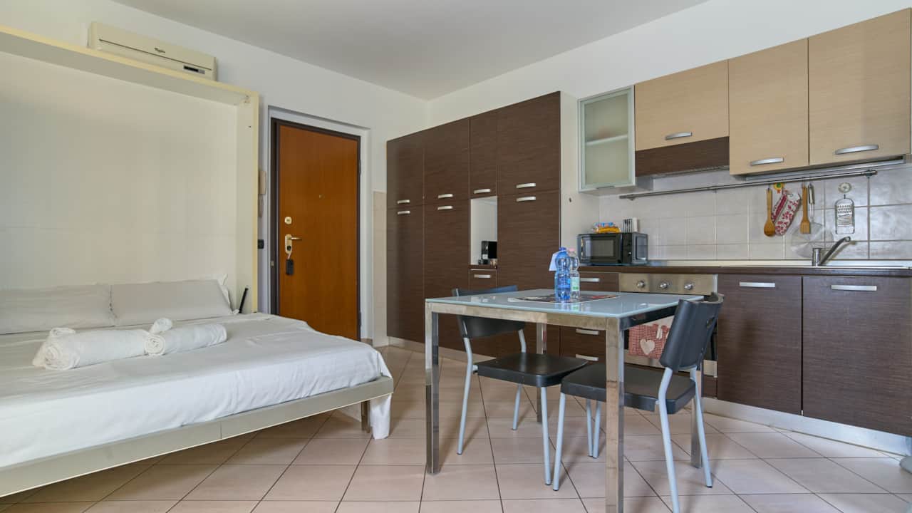 Bed next to the entrance with dining area and kitchen at the back