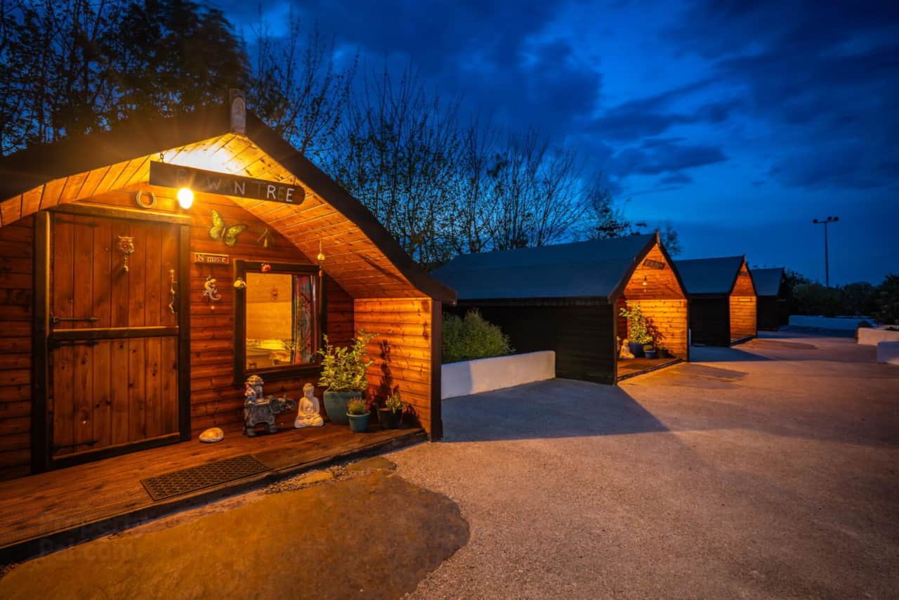 Four glamping pods at dusk at The Hideaway Muff, Donegal, with warm interior lighting