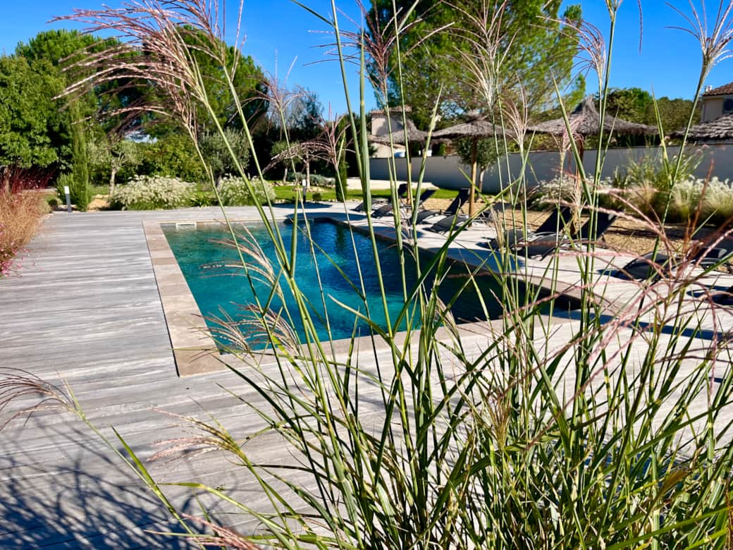 The swimming pool with its exotic wood terrace, sun loungers and parasols