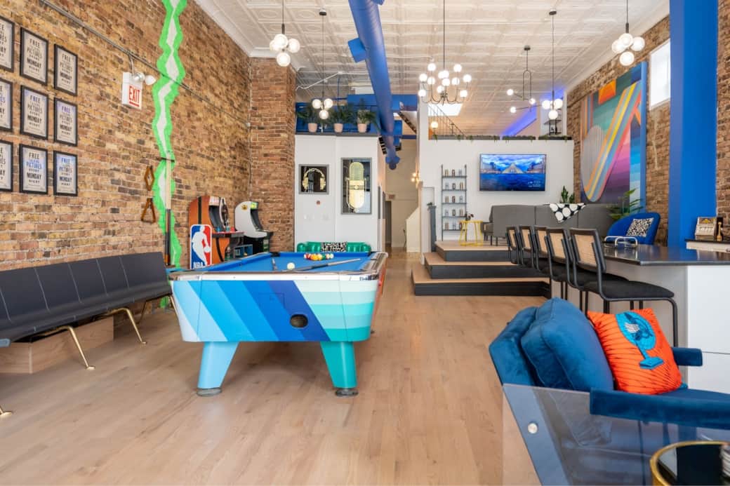 Open concept main room features plentiful seating, two 75" smart TVs, pool table, and more