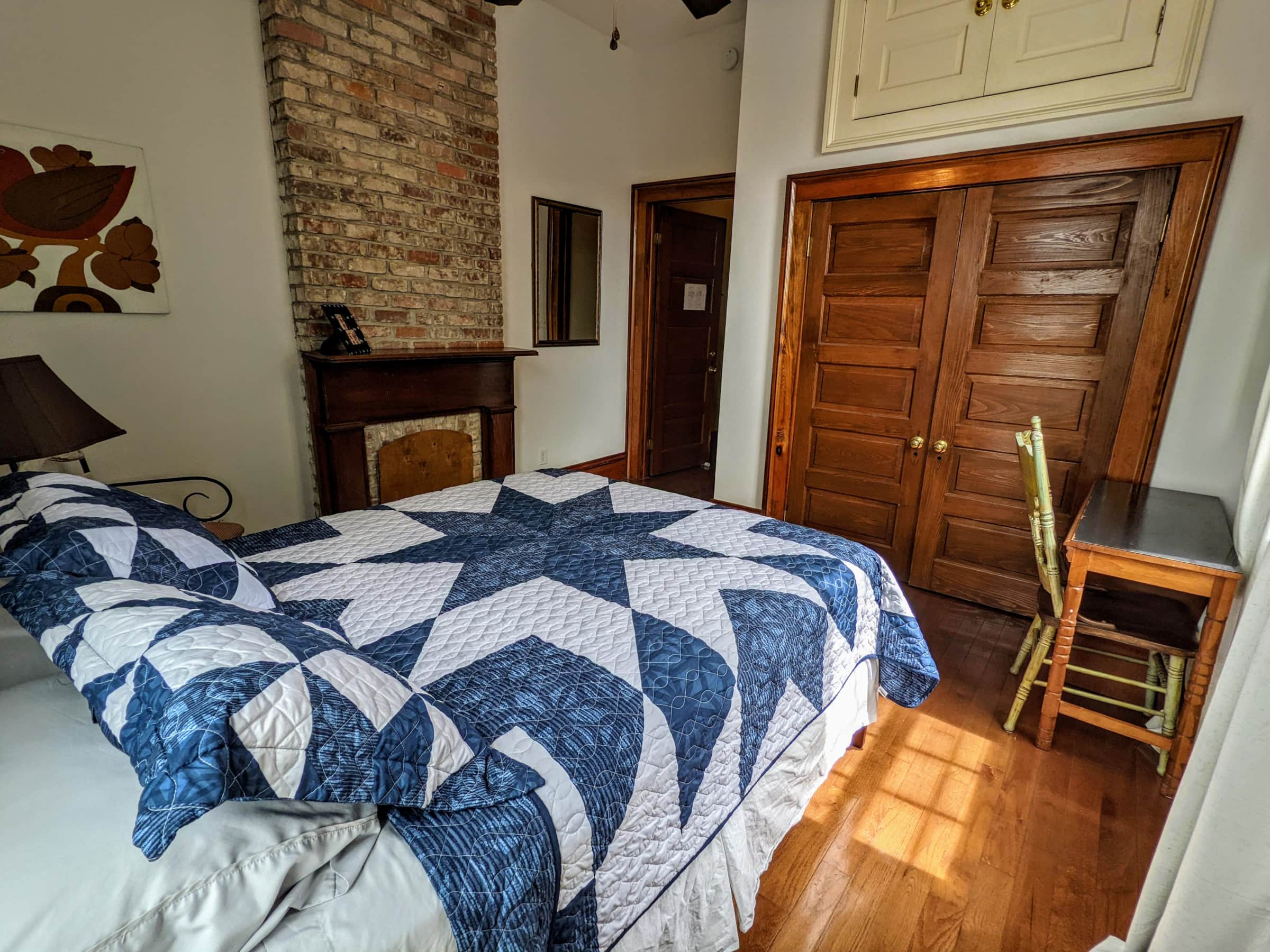 A guest room with a bed, desk, and fireplace