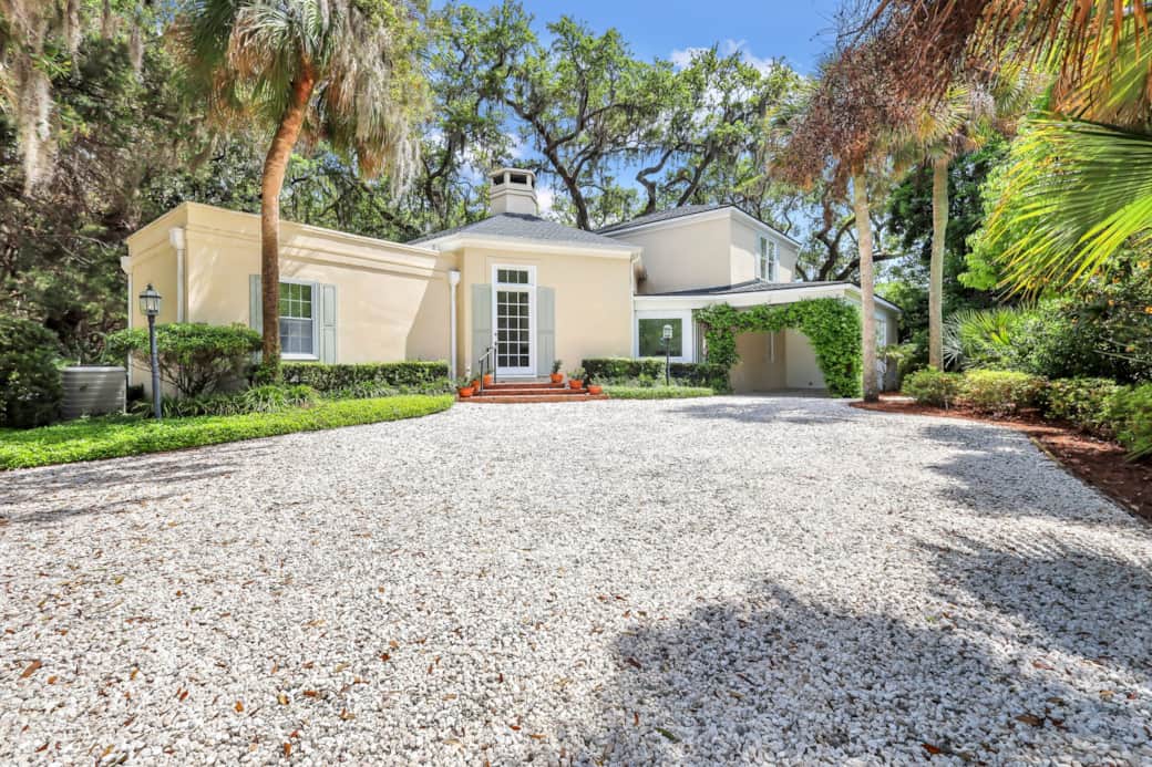 This beautiful property has an expansive driveway, with plenty of parking, and lots of greenery.