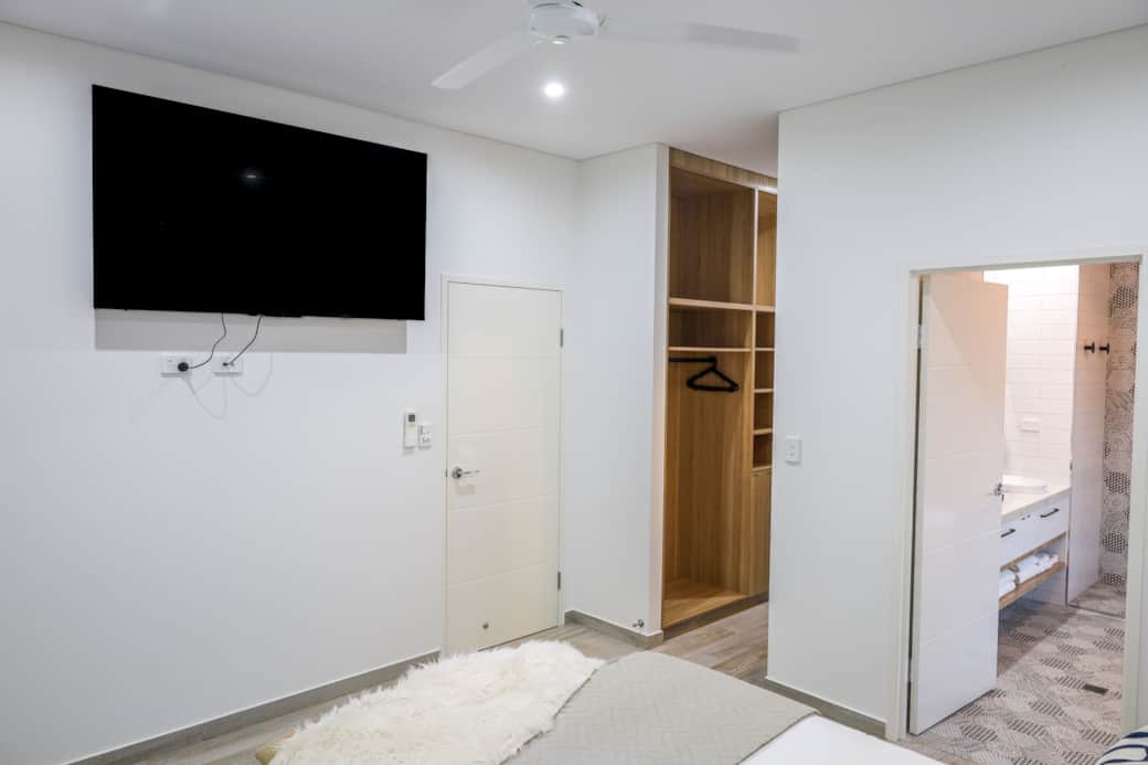 Wall-mounted smart TV in master bedroom for easy, comfortable viewing from your plush queen bed.