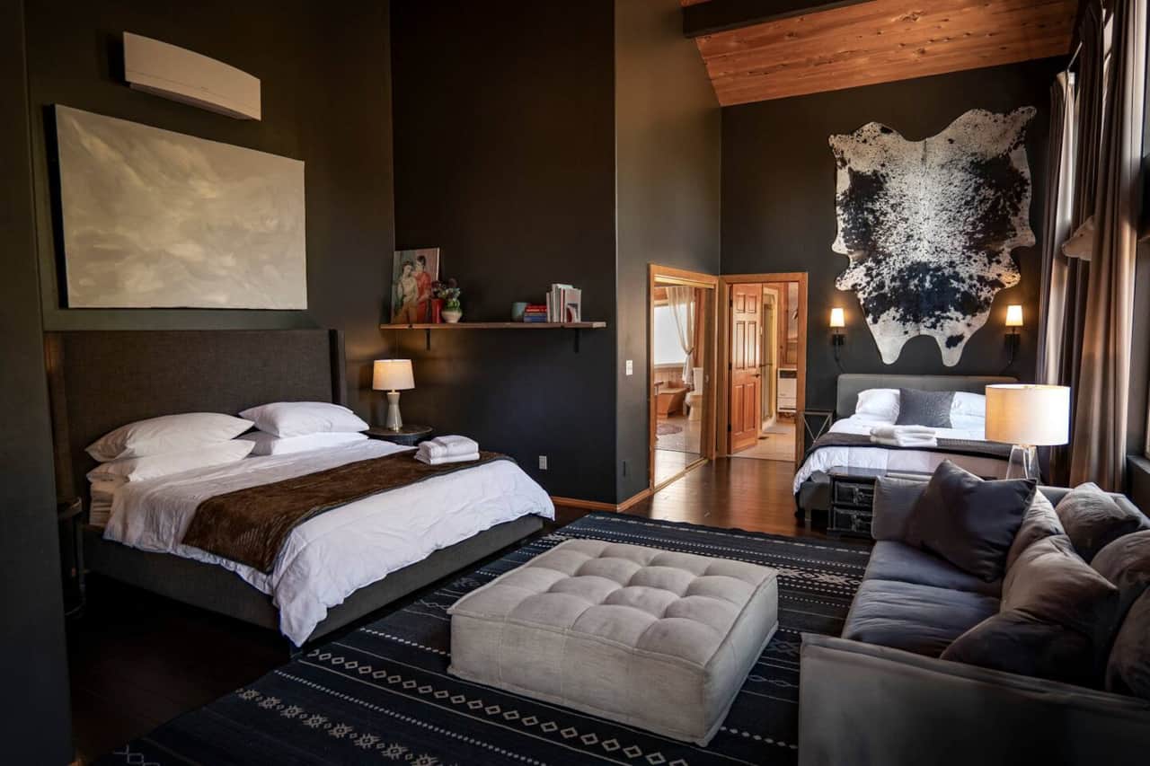 Huge Master bedroom with King bed and Queen bed, a lounge couch, 60" LG TV, black out curtains, and desk. Includes large walk in closet, ensuite bathroom, and access to front deck. 