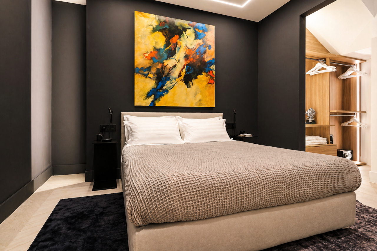 Schlafzimmer 12 Olbia, modernes Schlafzimmer, Doppelbett, dunkle Akzentwand, abstrakte Kunst, offener Kleiderschrank