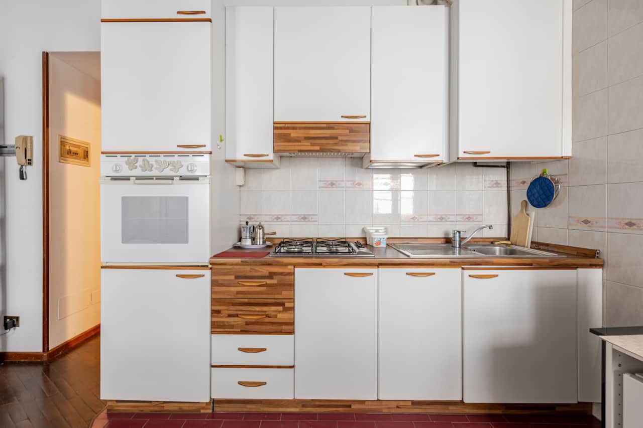 Cuisine blanche avec four, plaques de cuisson et placards muraux