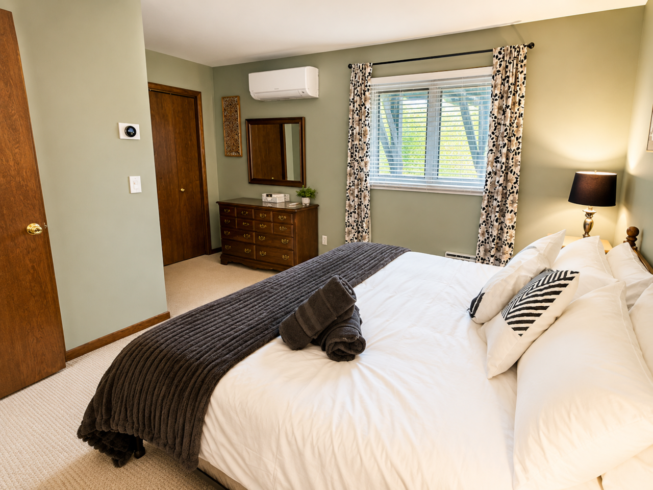 Primary king bedroom with plush bedding, peaceful wooded views, en suite half bath,and retreat vibes