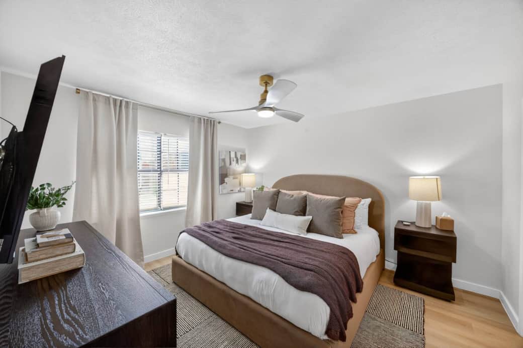 King bed with charging ports in nightstands featuring a 55" Smart TV, dresser, walk in closet, and en suite bathroom with glass shower.