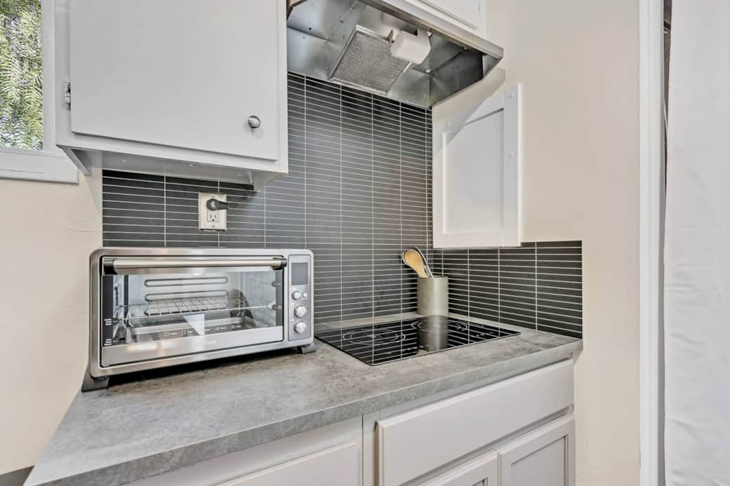 Compact kitchen setup with cooktop, toaster oven, and modern backsplash. Compact kitchen setup with cooktop, toaster oven, and modern backsplash.