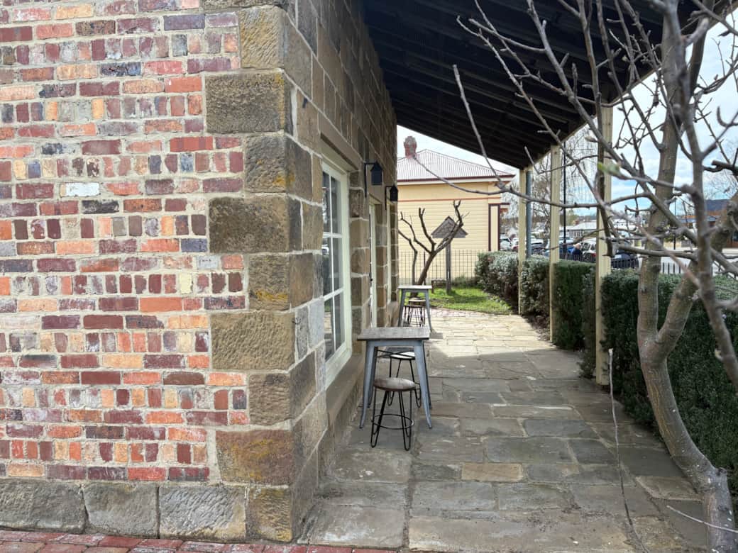 Relax on the stone veranda with café-style seating at the cottage entrance.