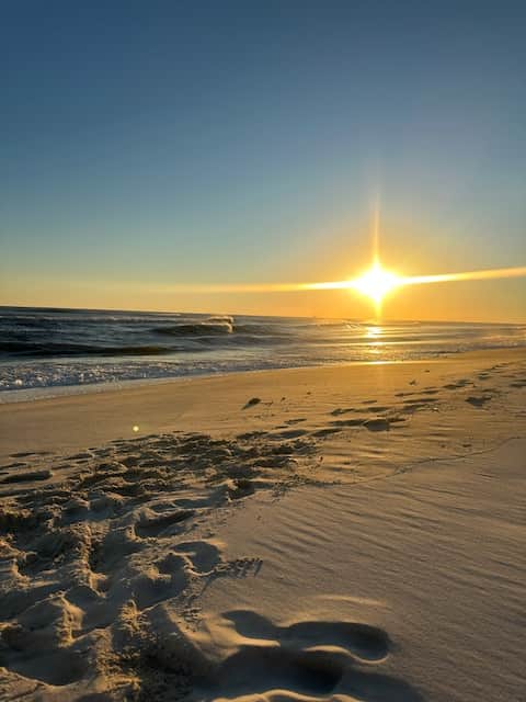 Couple enjoying a peaceful sunset walk along the soft sands of the Gulf Shores beach.