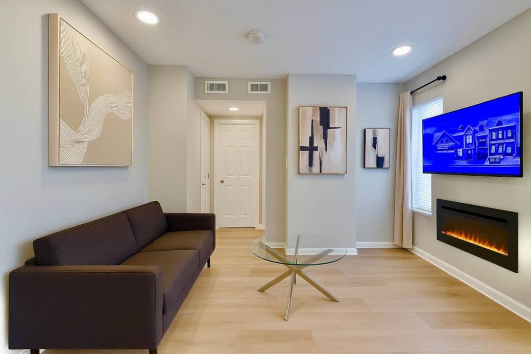 Cozy modern living room with a futon sofa, flatscreen TV, and electric fireplace for a warm, relaxing stay.