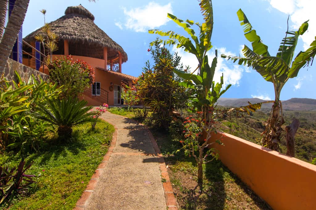 Garden path leading up to La Casa Redonda, with its palapa roof and tropical plants.