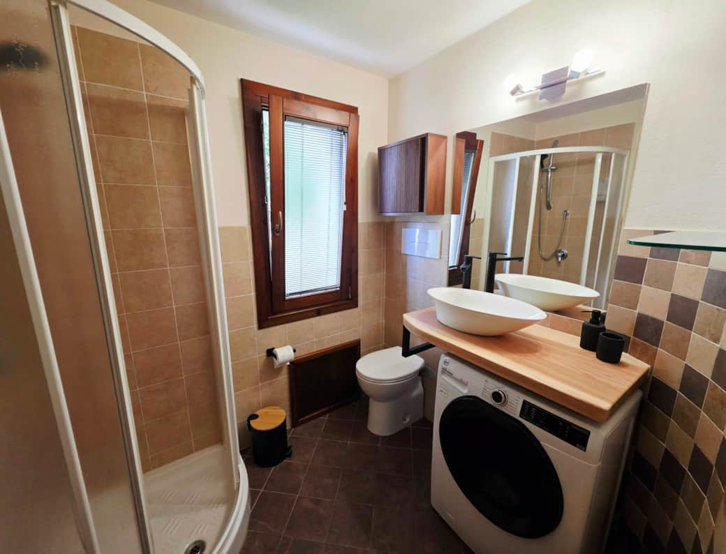 agno moderno rinnovato, con doccia spaziosa, lavabo da appoggio e finiture in legno naturale