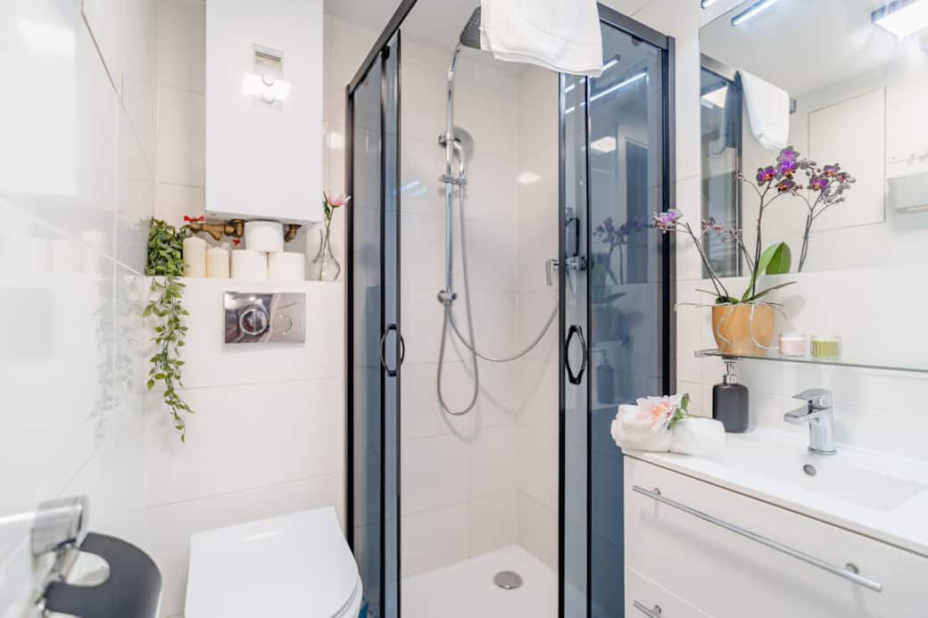 Nowoczesna łazienka z przeszkloną kabiną prysznicową, elegancką armaturą i funkcjonalną zabudową.