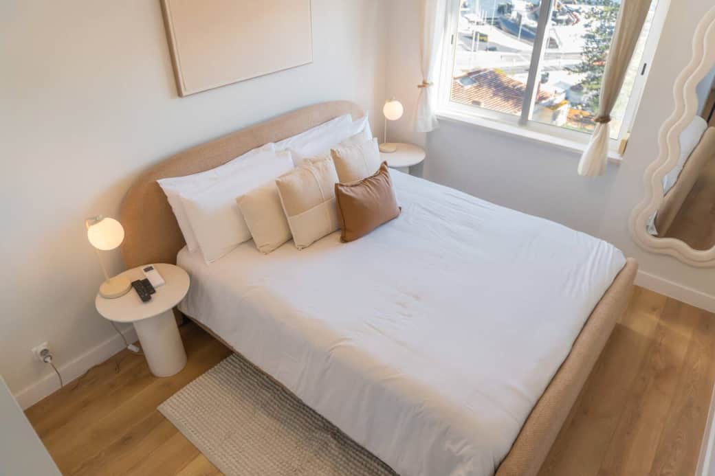 A full overview of the bright, stylish master bedroom, showing the comfy bed, modern decor, and window view.