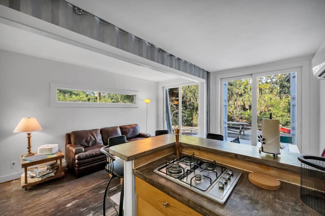 View from Kitchenette w/ 4-burner gas stove overlooking open living room & patio doors to the river