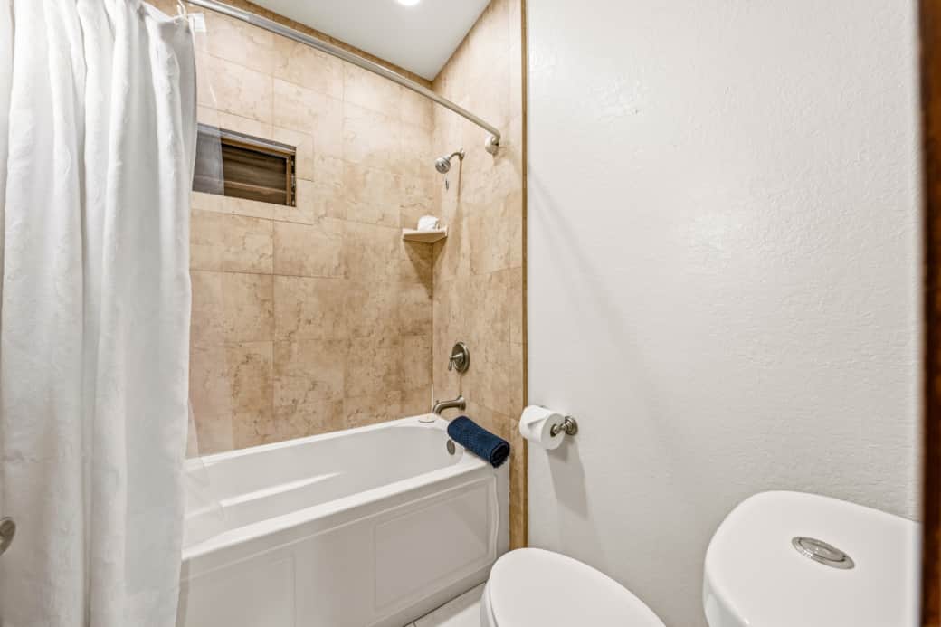 Clean tiled tub/shower combo perfect for rinsing off after a day at Poʻipū Beach.