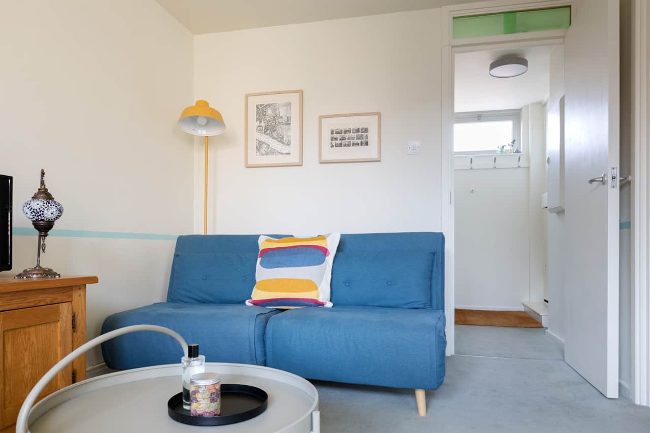 Blue day bed with statement cushion, looking toward the entrance hall