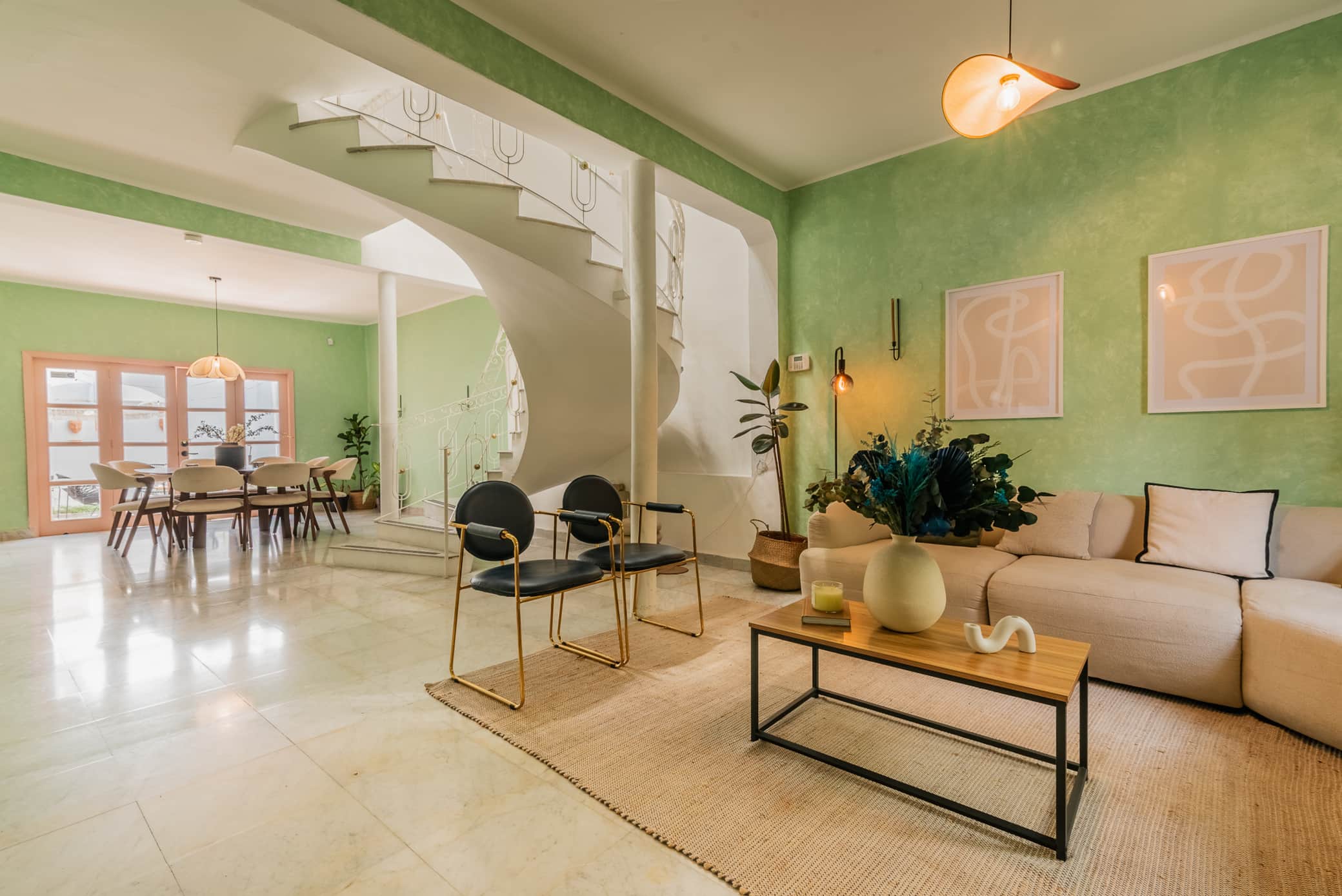 Sala y comedor con muros verdes y escalera de caracol en Casa Atlixco, La Condesa
