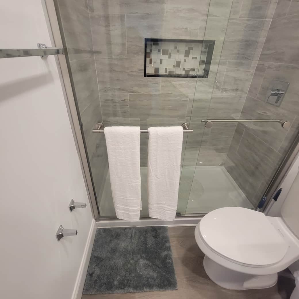 Modern tiled shower with glass door, bath mat, towels, and towel racks available. Lakeland, FL Modern tiled shower with glass door, bath mat, towels, and towel racks available. Lakeland, FL