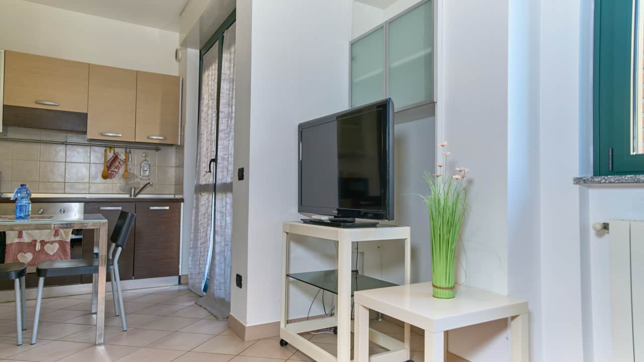 Open-plan studio with kitchenette, table and TV, in Monza