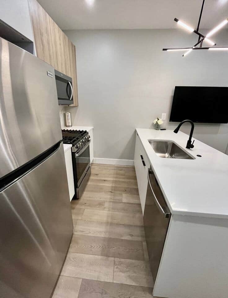 This modern kitchen is equipped with all your everyday amenities. It features high-quality cabinets, a refrigerator, a premium oven, a convenient microwave, a dishwasher, a toaster, a garbage disposal, and a stylish quartz island.
