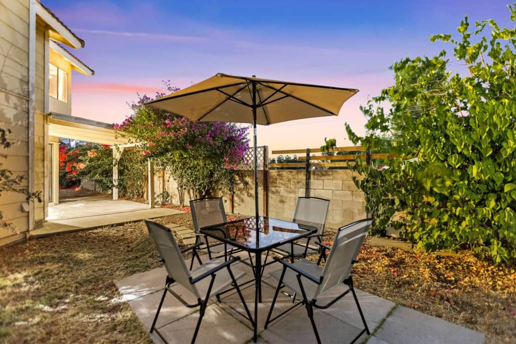 Dine alfresco under the umbrella with a cozy table setup - perfect for relaxing meals.