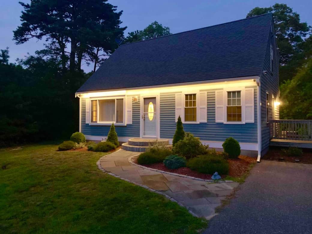 Charming exterior with lush greenery and welcoming lighting, your Cape Cod vacation haven from the moment you arrive. Charming exterior with lush greenery and welcoming lighting, your Cape Cod vacation haven from the moment you arrive.