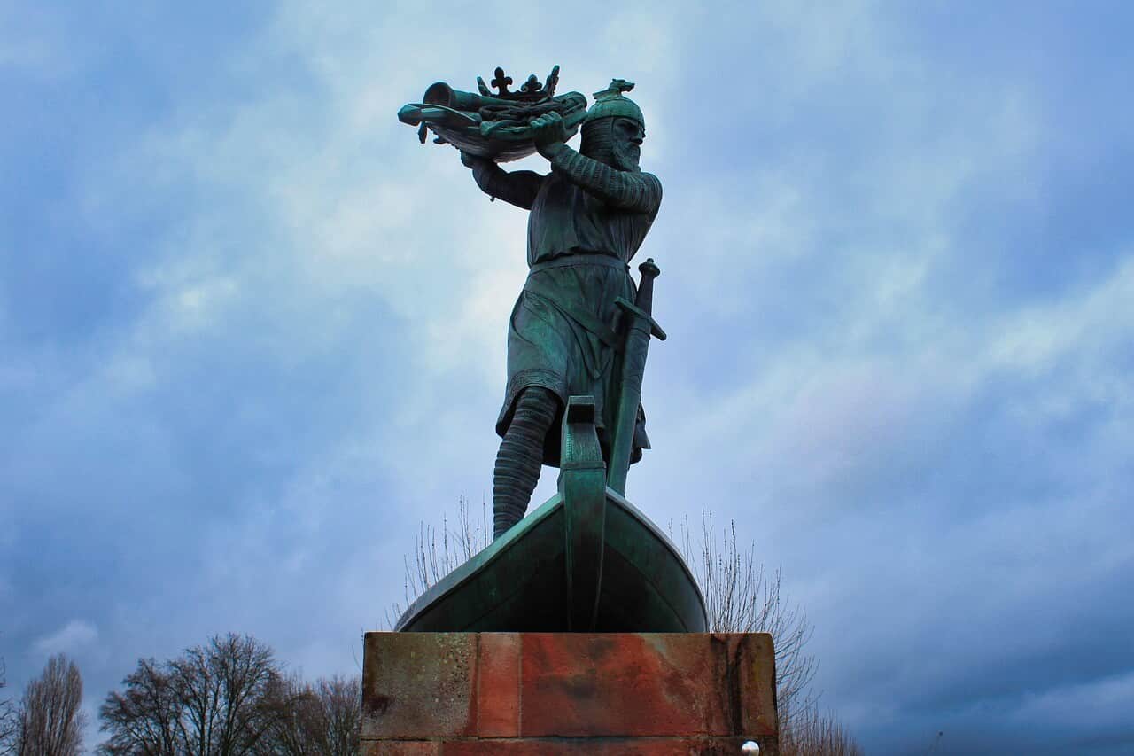 Hagen Monument in Worms showing a statue on a boat beneath a cloudy sky.