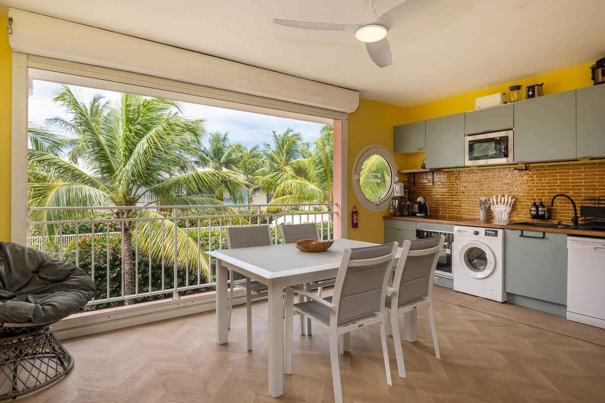 Véranda avec table, chaises, vue sur les palmiers et accès direct à la plage
