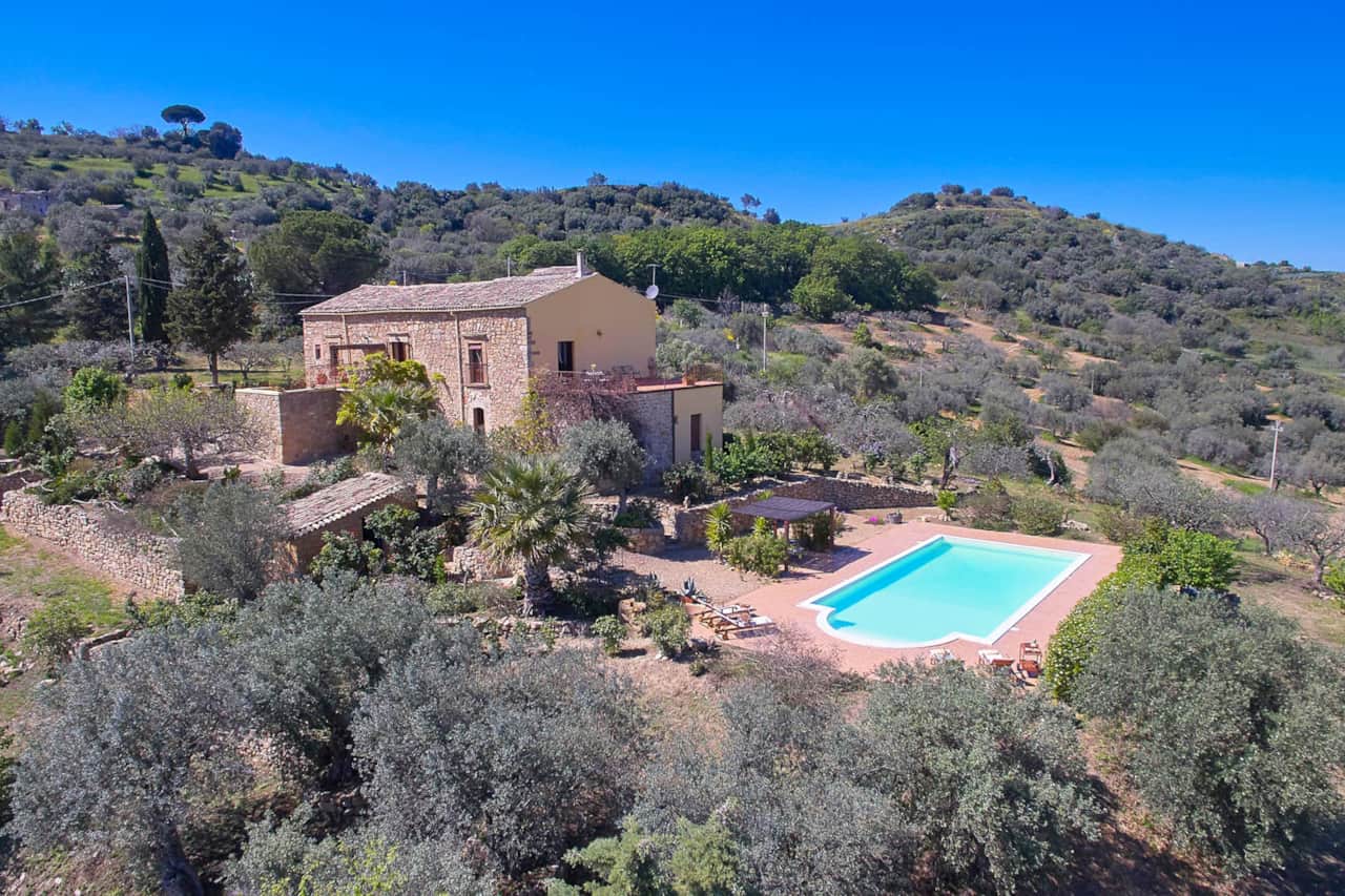 Vista aerea di Casa de Arena con piscina privata, grande giardino con ulivi e campagna siciliana.