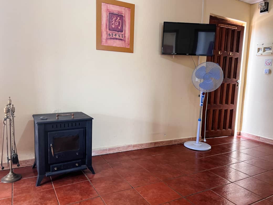 Sala de estar con estufa de leña, TV de pantalla plana y ventilador portátil
