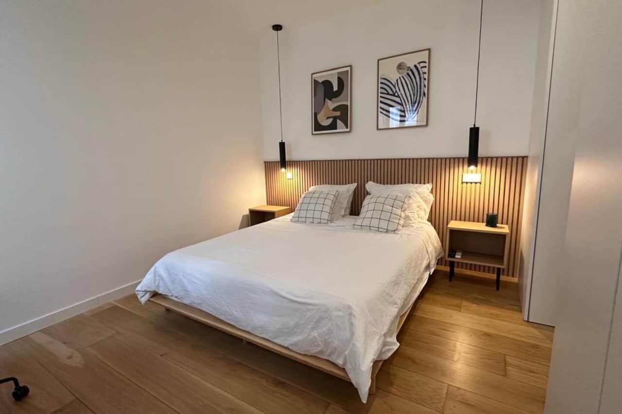 Dormitorio con cama doble, cabecero de listones y lámparas colgantes