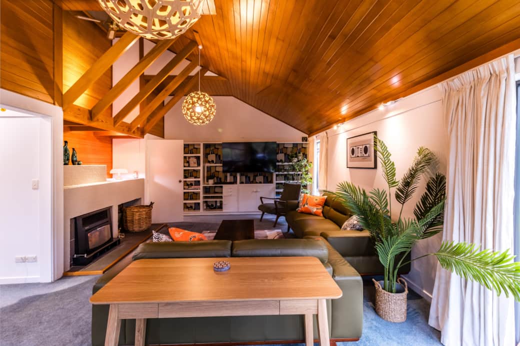Living room with timber ceilings, leather couches, and a big ol’ TV for epic chill time.