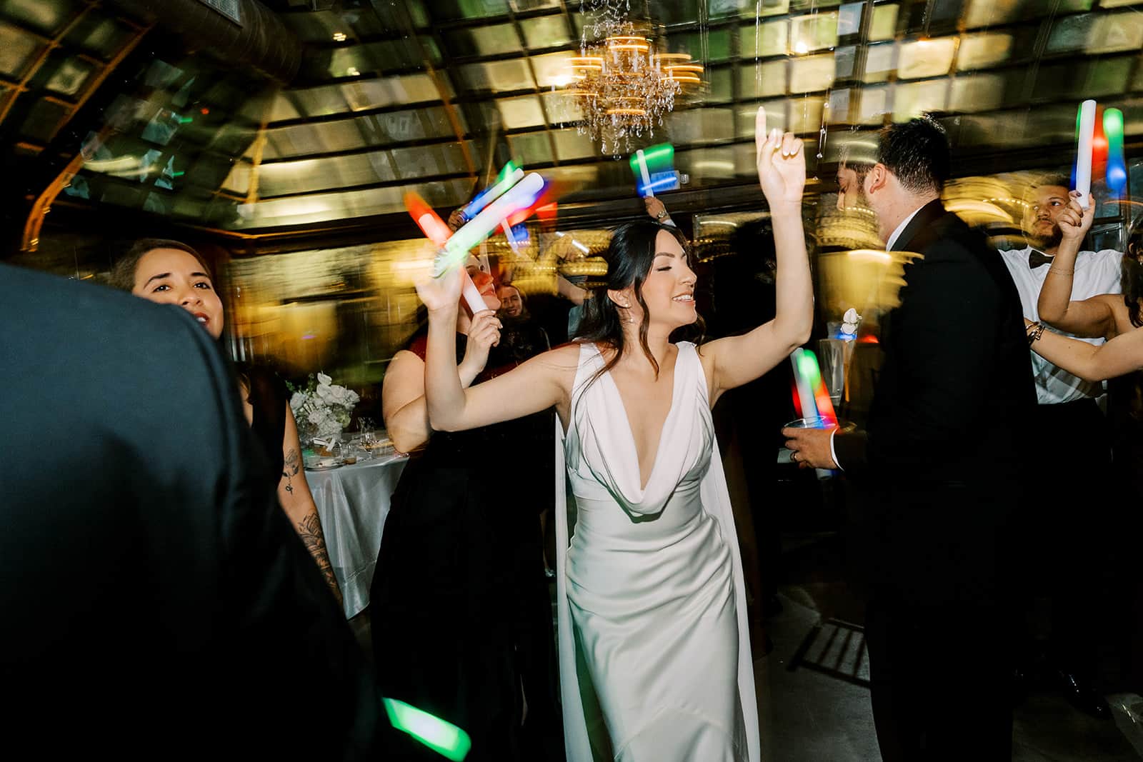 Bride dancing with friends under lights at a Bryan Museum wedding reception in Galveston, Texas