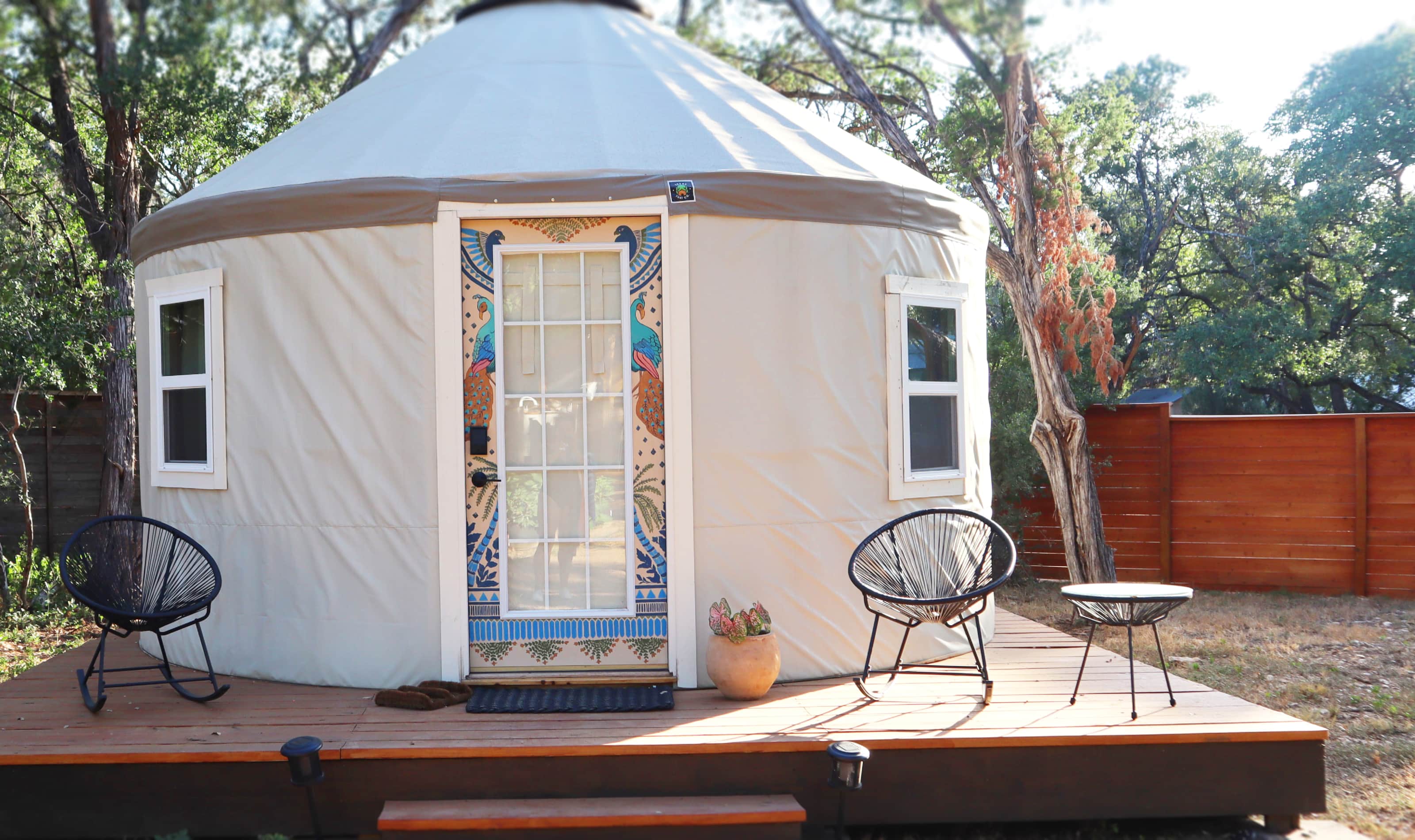 A white yurt with a wooden deck and outdoor furniture