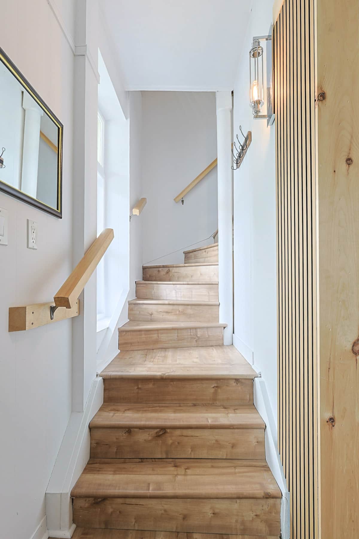 Escalier en bois clair menant à l’étage — design épuré et chaleureux, baigné de lumière naturelle.