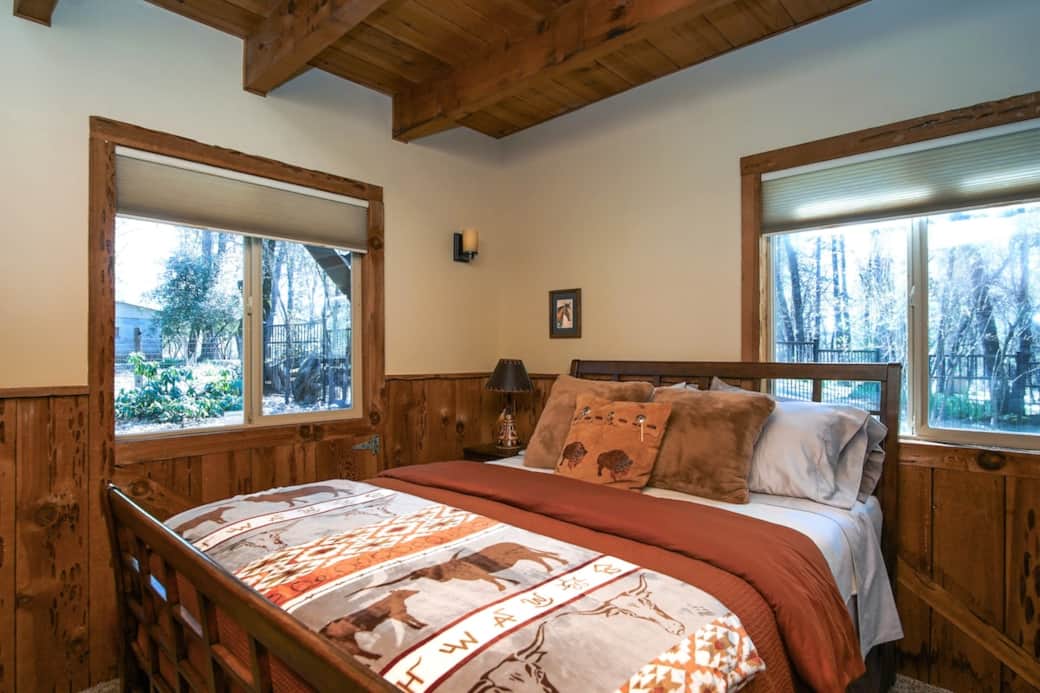 Settle into The Prairie Bison Room. Featuring beautiful wood wainscoting, vaulted ceilings with exposed beams, and wrap-around forest views, this cozy sanctuary blends authentic Western charm with ultimate comfort. Your perfect peaceful escape.