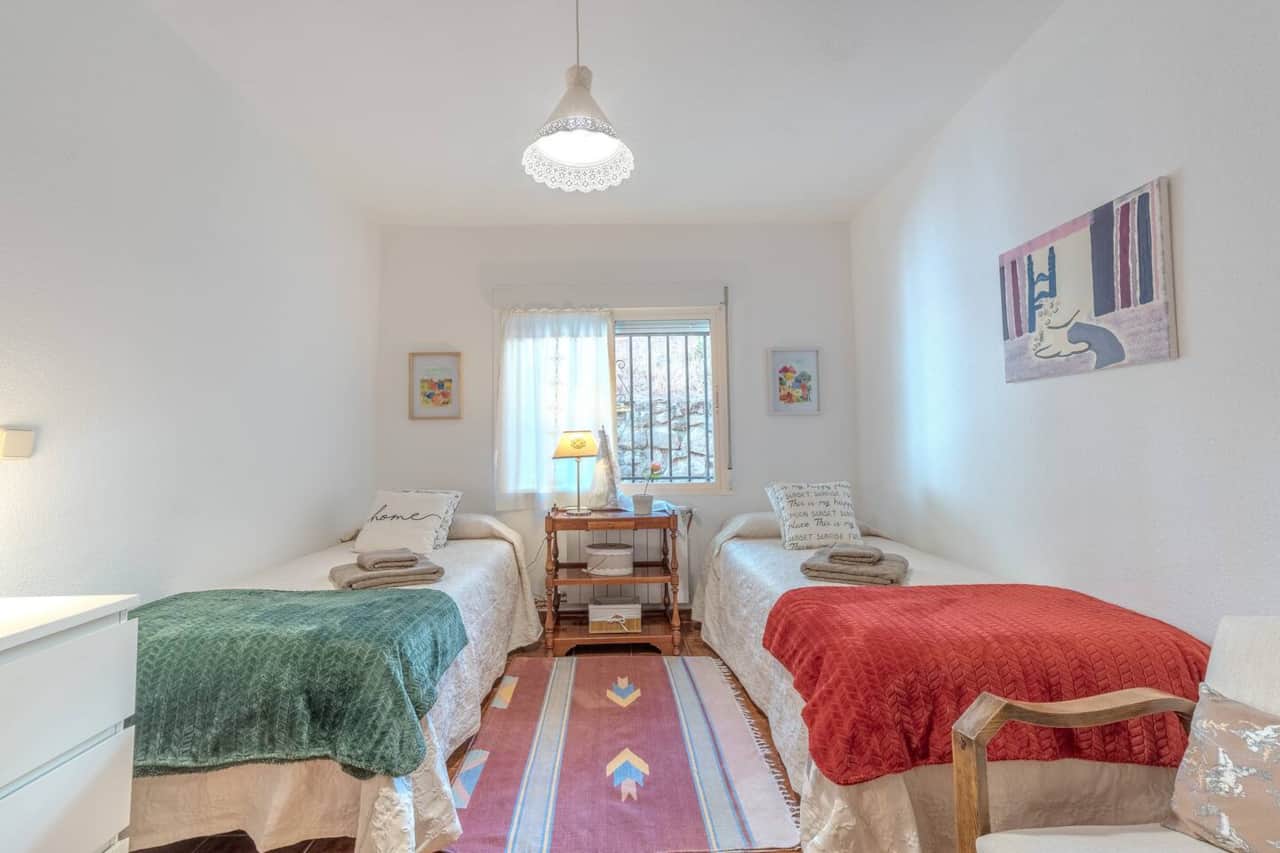 Dormitorio con dos camas y ventana al jardín