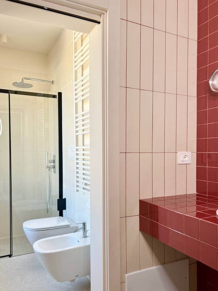 The modern bathroom mixes metals & high gloss red tile vanity