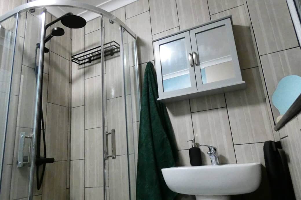 Main bathroom featuring shower cubicle with rain shower head, toilet, storage cupboards, toiletries