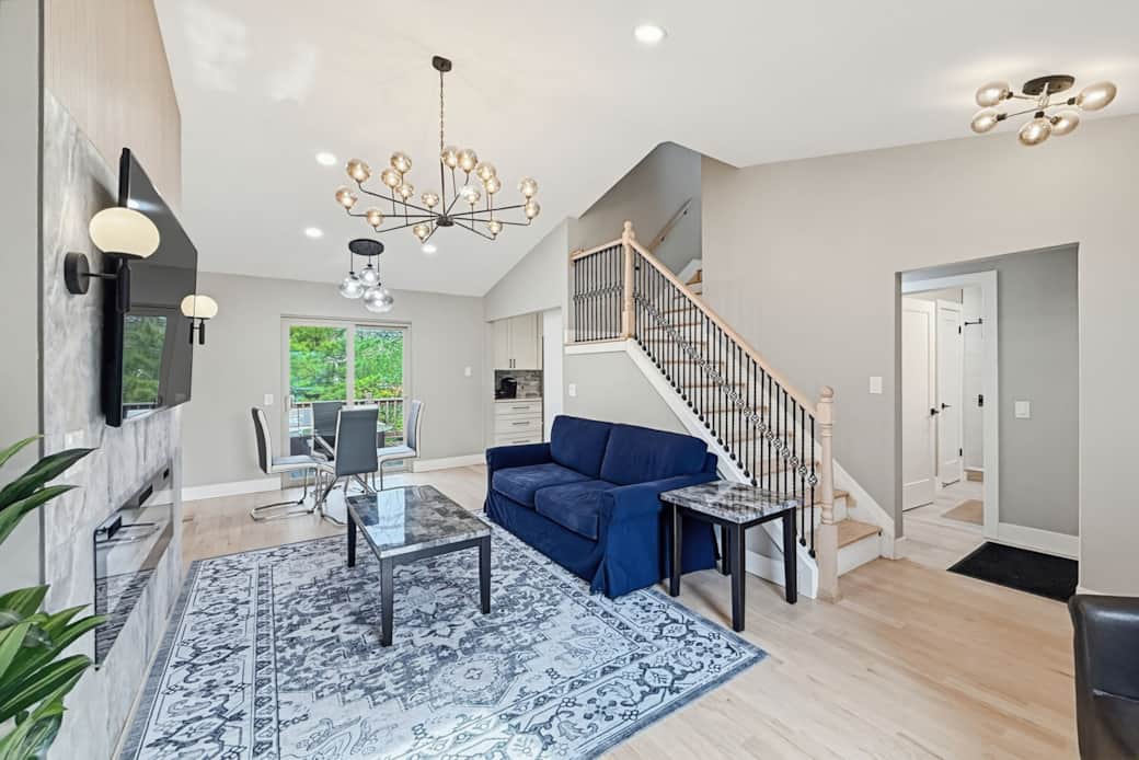 Living Room 1: Sun-drenched main living area with vaulted ceilings and a large flat-screen TV.