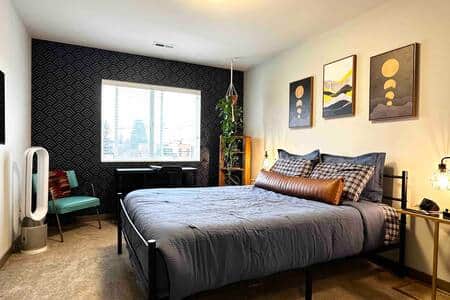 Large room with queen bed, mini fridge, microwave and TV all logged into streaming platforms.