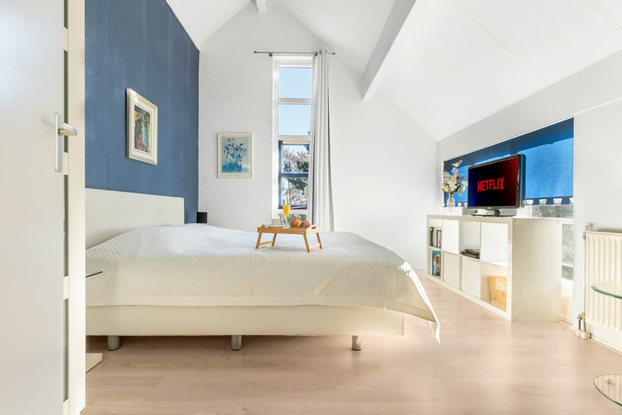 Hauptschlafzimmer im Obergeschoss mit großem Doppelbett, Fernseher, Leseecke und Kleiderschrank